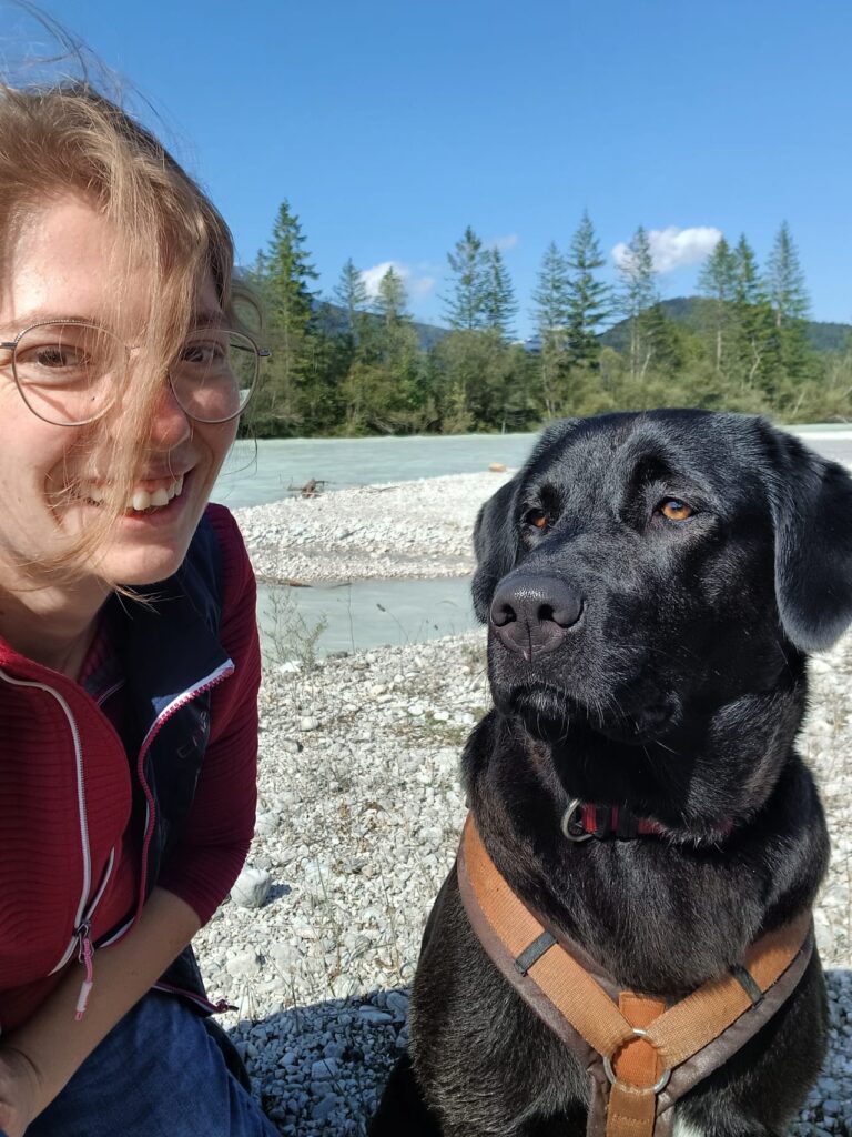 Frau mit Hund an sonnigem Tag am Wasser